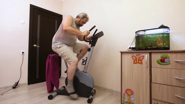 man engaged on exercise bike in room