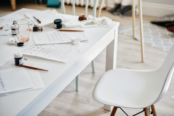 working space in light color, a chair and a table for work on calligraphy.