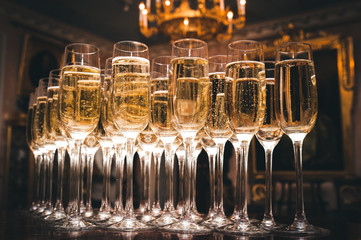 A lot of glasses of champagne in a luxurious atmosphere. Stylish, toned photo. Secular reception, new year, wedding - obrazy, fototapety, plakaty