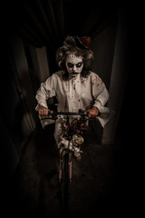 Night ride with dolls.Creepy clown girl riding a bicycle with dolls in a scary room