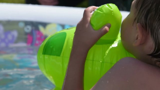 Close-up shot of little boy bathing with rubber frog in outdoor pool. Summer fun in water