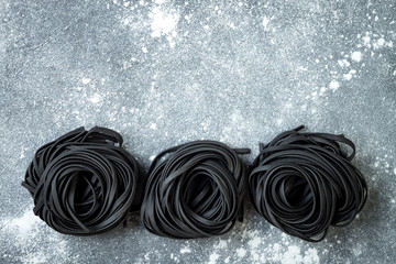 Detox charcoal or black squid ink fettuccine on grey background. Copy space