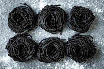 Detox charcoal or black squid ink fettuccine on grey background