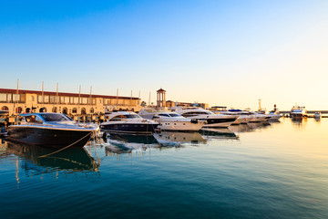 Fototapeta na wymiar Luxury yachts and motor boats in sea port at sunset.