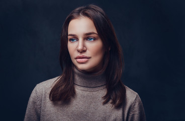 A woman dressed in a long neck brown jacket.