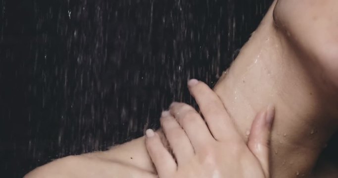 Woman taking shower in slow motion 120fps. dolly shot. Young beautiful woman taking a shower gently touching her skin. Close up on neck and shoulder. Beauty and relax concept. Filmed in 4K DCi RAW.