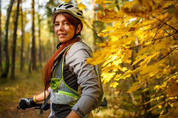 Photo of girl in helmet on bicycle in autumn forest