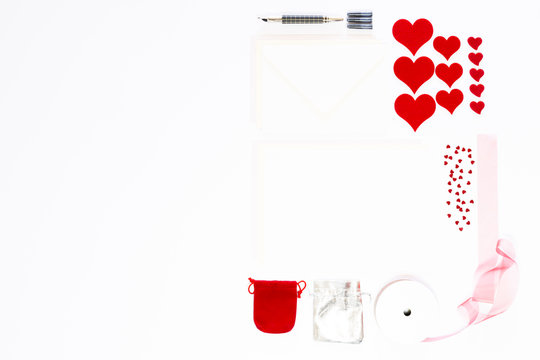 Display of love letter items on white background. Assortment of cards, envelopes, hearts, ribbon and ink pen.