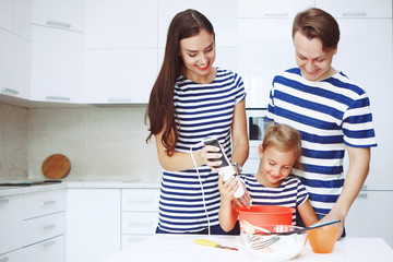Adorable happy family makes cakes together on your white kitchen.