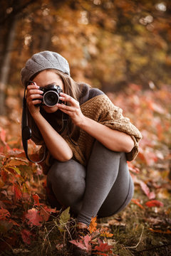 young woman taking pictures  in autumn forest