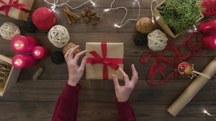 Top view hands unwrapping christmas presents at wooden desk from above with christmass decoration