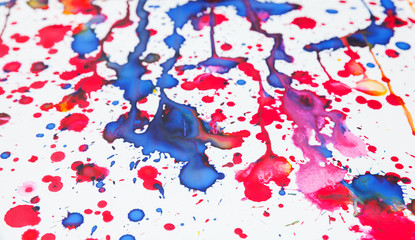 Colorful paint splashes on white paper, closeup