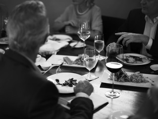 Group of people having dinner in the restaurant together grayscale