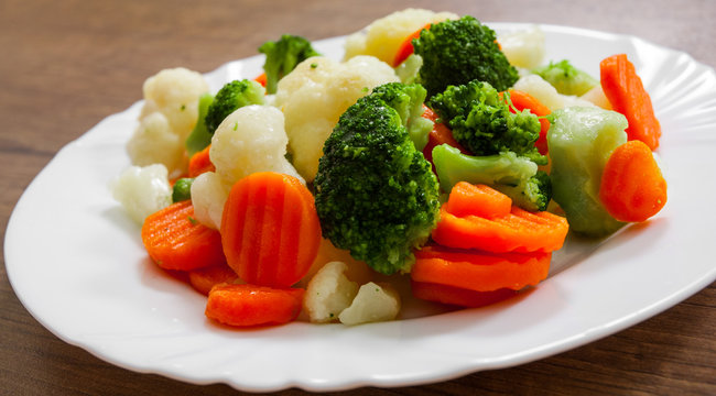 Mixed vegetables. cauliflower, broccoli and carrots in plate on a wooden background.