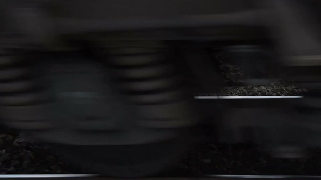 Rail tracks and train passing by on high speed, view to the wheels