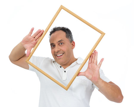 Funny man holds frame frame around face. He is overweight and is wearing a white polo..