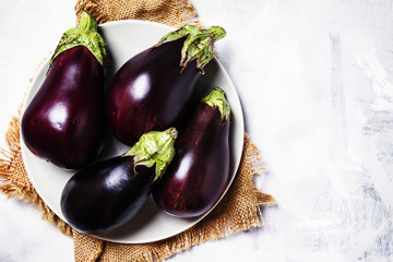 Fresh purple eggplants on plate, top view