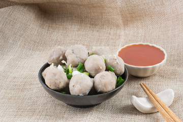 boiled meatballs in a ceramic dish on calico fabric background, close up.
