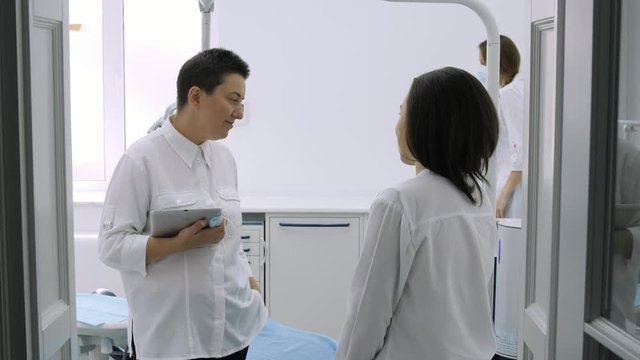 Dentist talking with young female patient in at the dentist clinic.