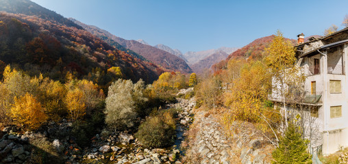 Piedicavallo, Italy - October 20, 2017: Rustic alpine houses and the Cervo river in the village of Piedicavallo with a beautiful autumn scenery