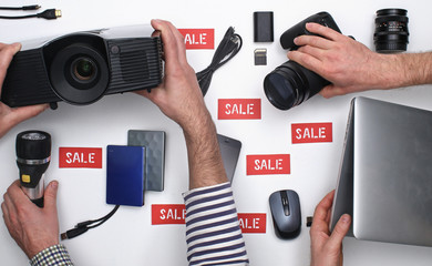 Top view on hands taking electronic products with SALE label on white background. Black Friday concept. 