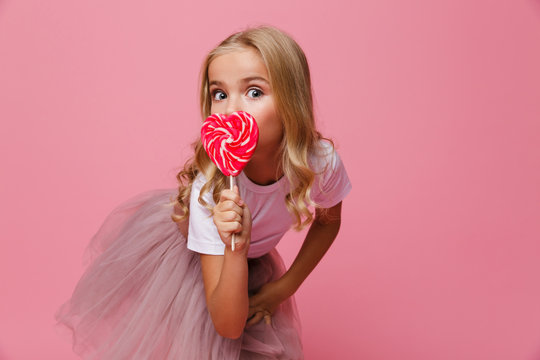 Portrait of a pretty little girl holding heart shaped lollipop