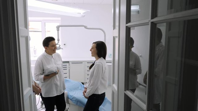 Dentist talking with young female patient in at the dentist clinic.