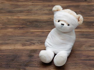 Portrait of cute mummy teddy bear doll bind with white gauze or bandage on dark wooden background used as background, wallpaper, or backdrop in Halloween, festival, and decoration theme