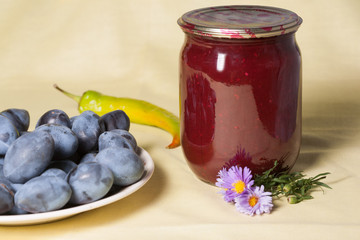 Tkemali Georgian sauce. glass jars with canned sauce. Fresh plums in a plate.