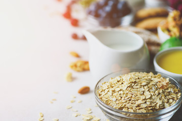 Organic ingredients for healthy breakfast - berries, milk, egg, oatmeal on grey concrete background. Copy space. Healthy breakfast concept. Sunny morning
