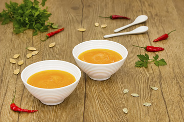 A  vegetarian cream soup of pumpkin on a wooden table. Soft focus.