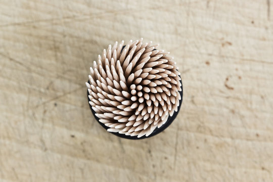 Box of toothpicks on wooden board seen from above
