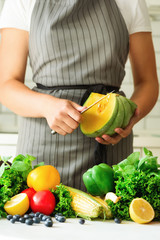 Woman peeling pumpking, vegetables, onion, tomatoes, corn, bell pepper, spinach, lettuce leaves. Clean eating, detox concept
