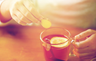 close up of woman adding ginger to tea with lemon