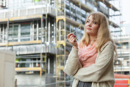 Woman with keys on front of new house building