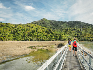 Two backpackers are walking into the Abel Tasman Coast Track in the South Island, New Zealand.