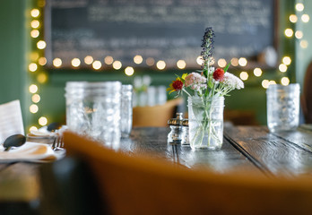 Table setting at a rustic restaurant with jars and floral centerpiece