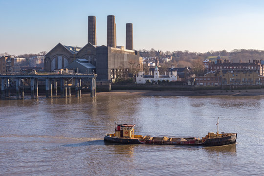 Cargo ship with full load, travelling up the Thames and passing the Greenwich power station.