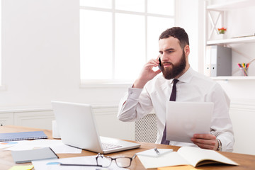 Naklejka premium Serious businessman with laptop in modern white office