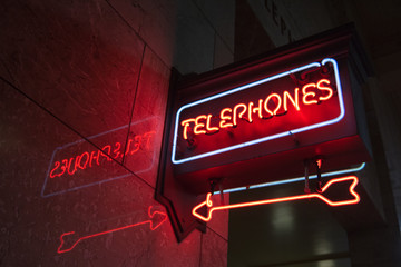 Neon "Telephones" sign with a pointing neon arrow inside a building