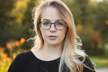 Beautiful woman in glasses on a autumn yellow background closeup portrait