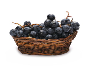 Dark grapes in wooden wicker basket, isolated on white background