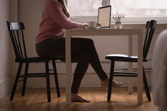 Low section of woman using laptop at table