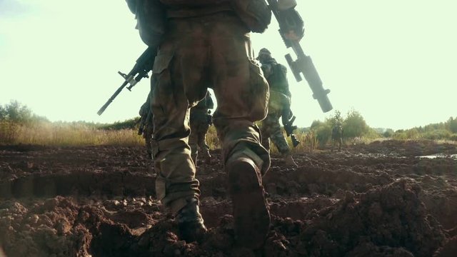 Military soldiers with weapon walking on dirty road