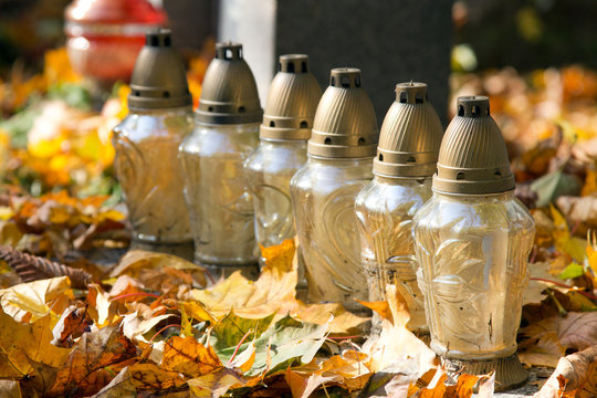 Votive candles at the grave with autumn leaves.