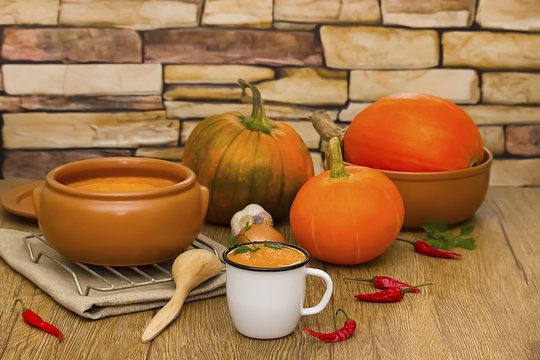A bright cream soup of pumpkin and whole pumpkins on a wooden table.