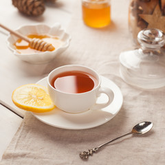 Cup of tea with honey and lemon on wooden table, winter still life, breakfast