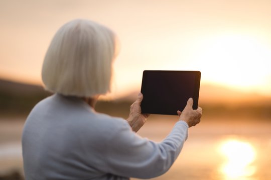 Senior woman using digital tablet at beach