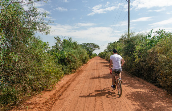 Young hipster man riding a bicycle in the middle of an orange dirt road