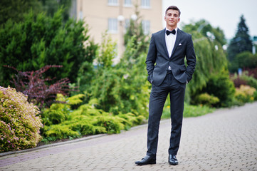 Portrait of a handsome young man in formal fancy suit posing on the pavement in the park on a prom day. - obrazy, fototapety, plakaty